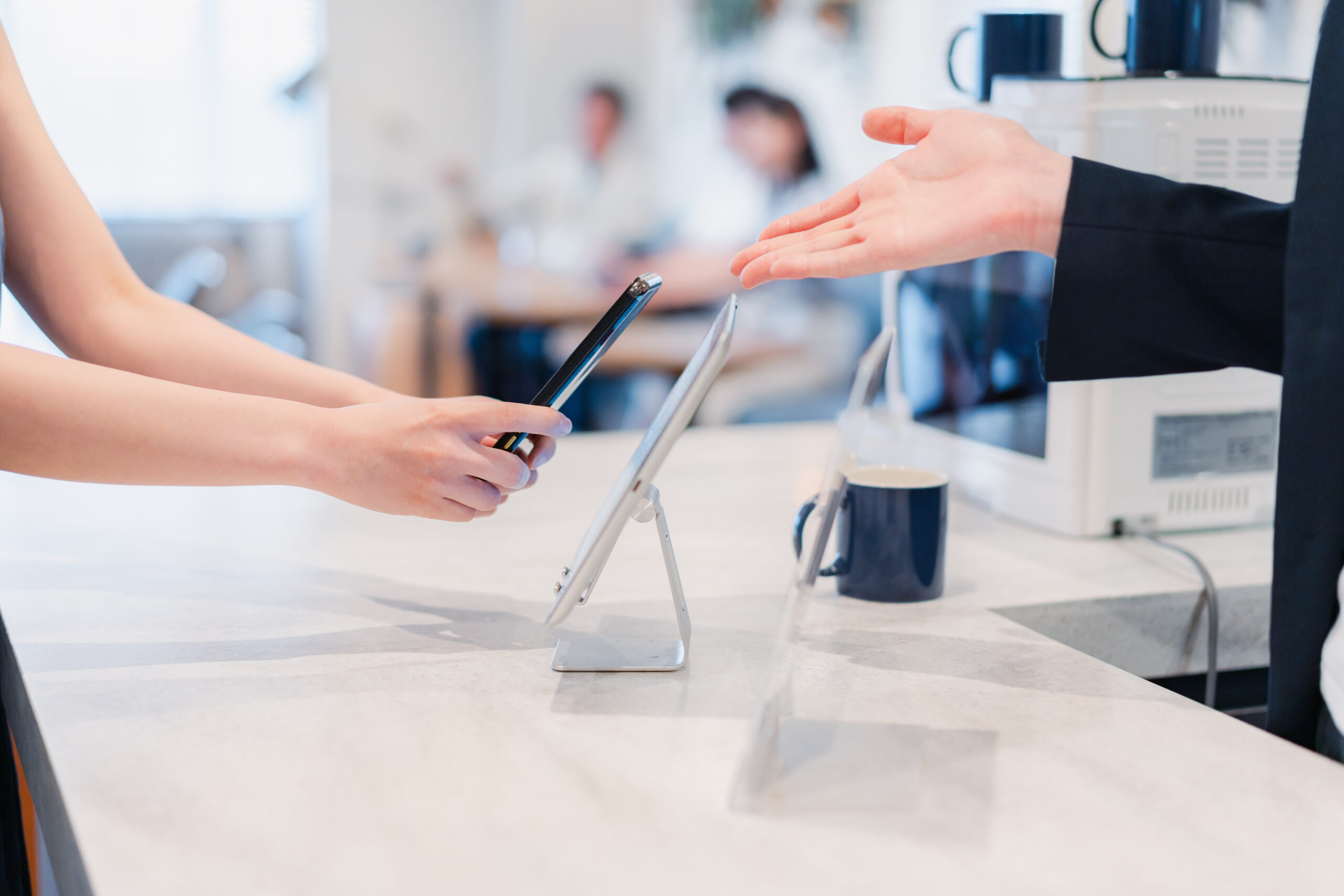 タブレットに携帯をかざす女性